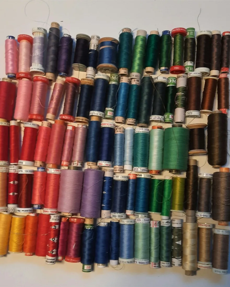 Carretes e hilos de bordado ordenados por gamas de color sobre una mesa de taller